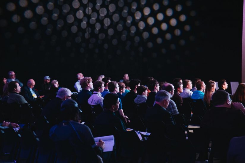 Ein Bild von einem Konferenzraum mit vielen Menschen, die aufmerksam zuhören.